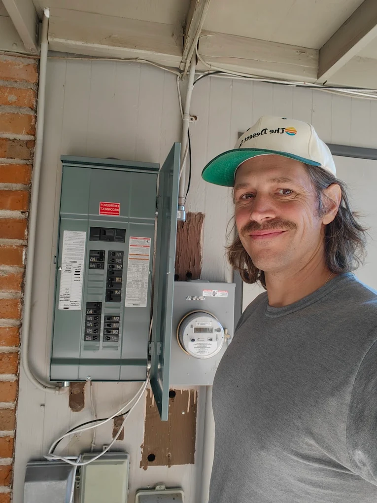 Aaron Clark of Light The Way Electrical beside a newly installed breaker panel and meter