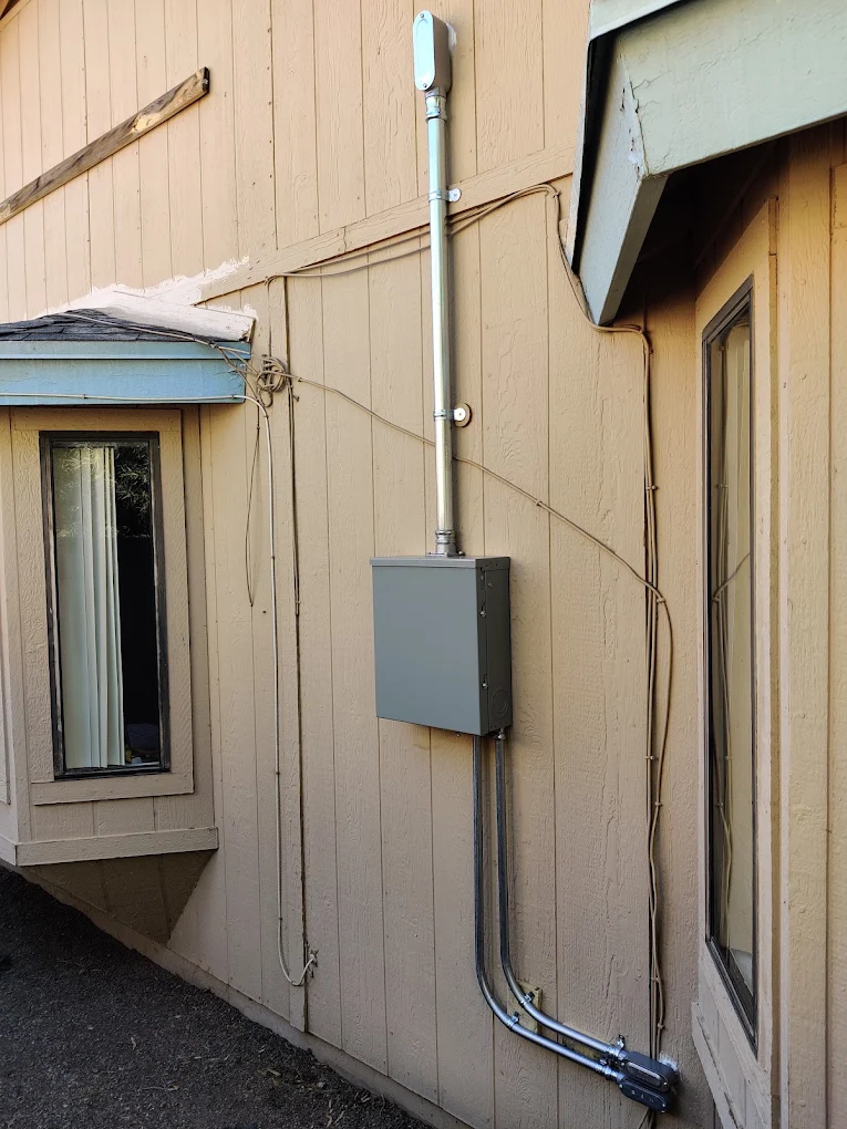 Exterior metal conduit run to a new disconnect box on a wood-sided home