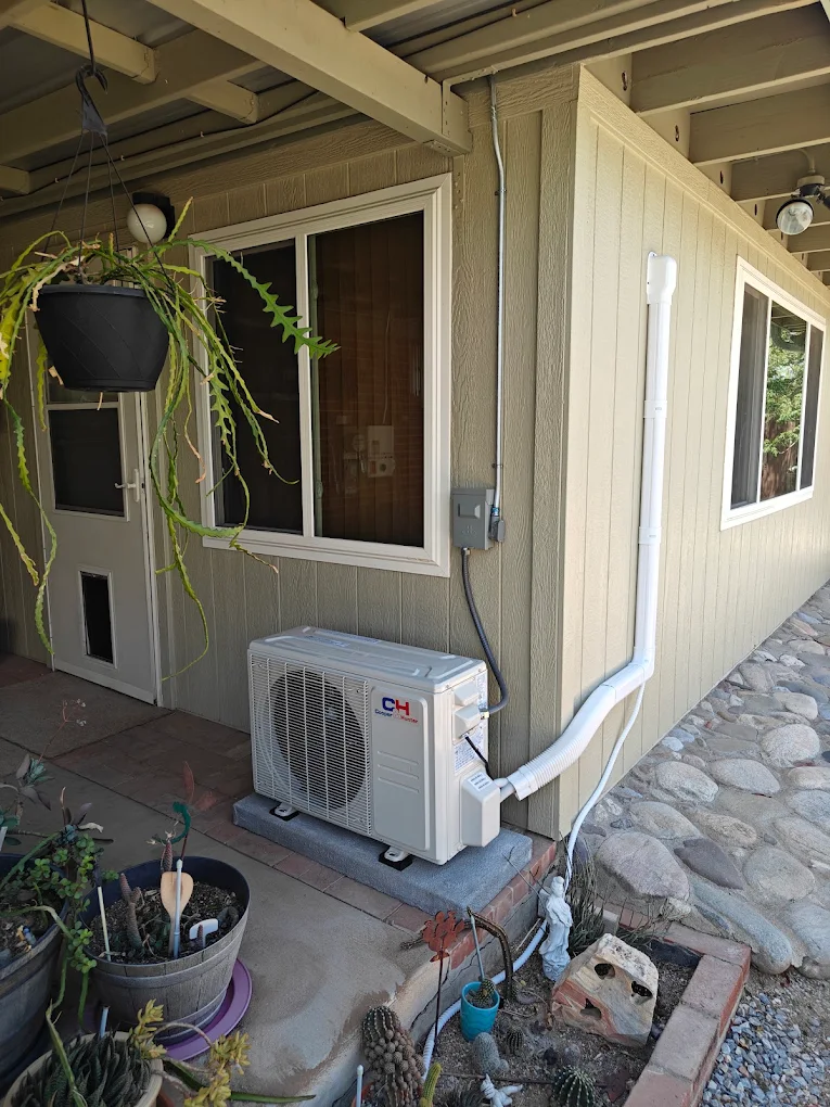 Ductless mini-split condenser on a concrete pad with a white line-set cover beside a Tucson patio