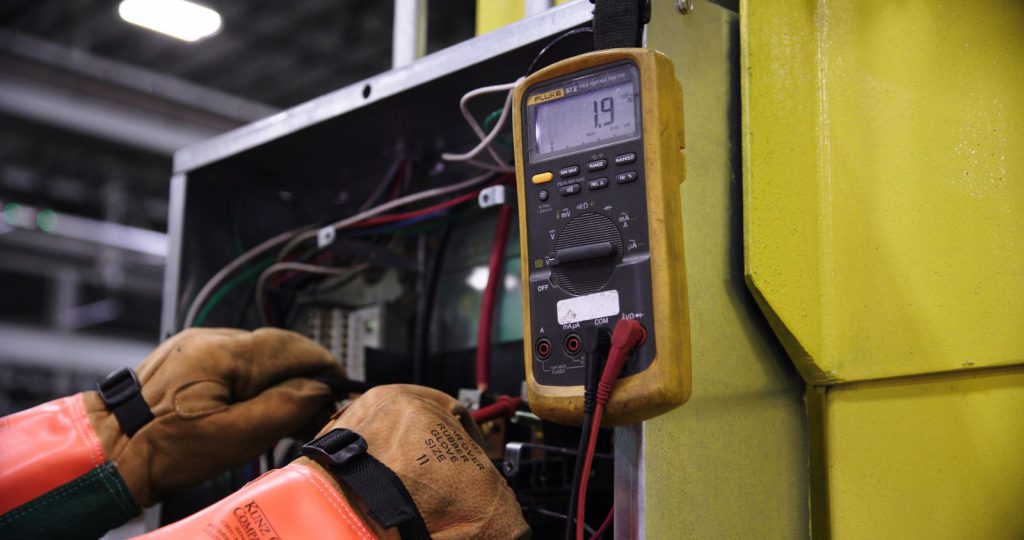 Electrician testing a circuit with a multimeter (placeholder photo)